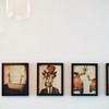 A modern interior display of four framed giraffe-themed artworks, enhanced by warm lighting.